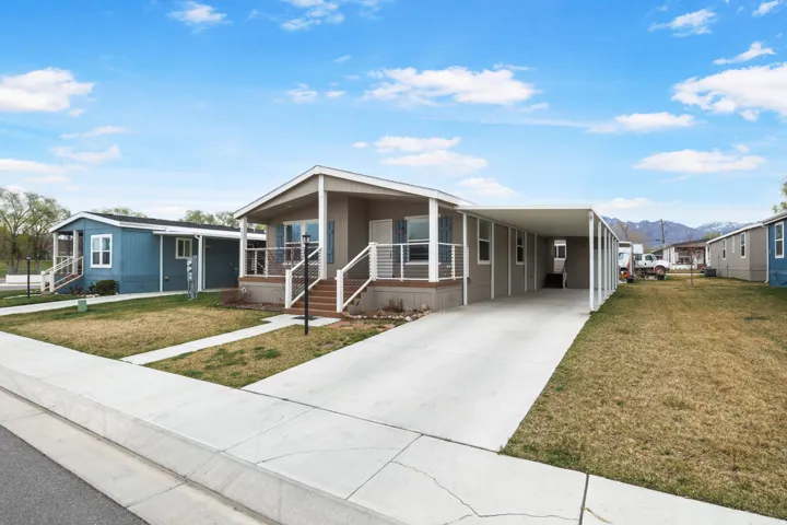 Manufactured / mobile home featuring a front lawn, an attached carport, covered porch, a mountain view, and concrete driveway