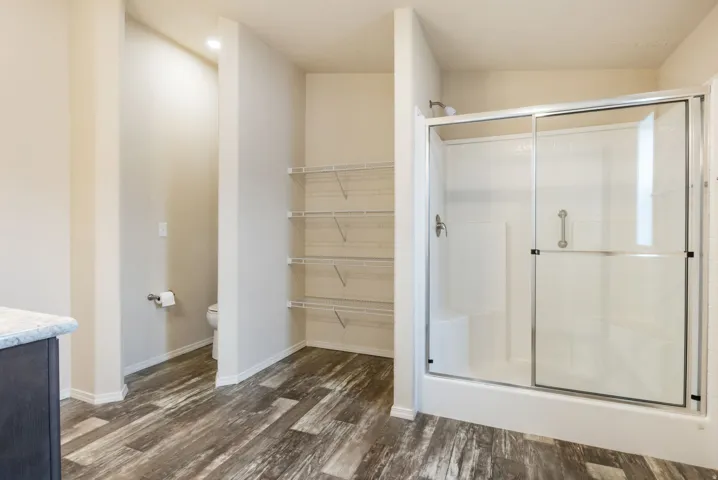 Full bathroom featuring vanity, a shower stall, and dark wood-style floors