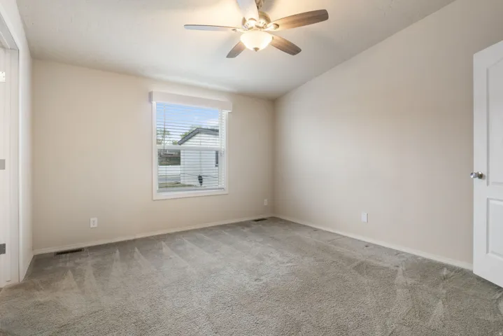 Empty room with lofted ceiling, light colored carpet, and a ceiling fan
