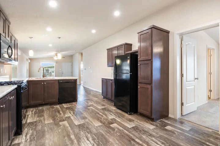 Kitchen featuring black appliances, a peninsula, dark wood-style floors, dark wood finish cabinets, and recessed lighting