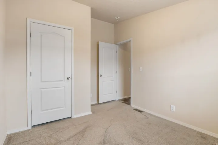 Unfurnished bedroom featuring light carpet and baseboards