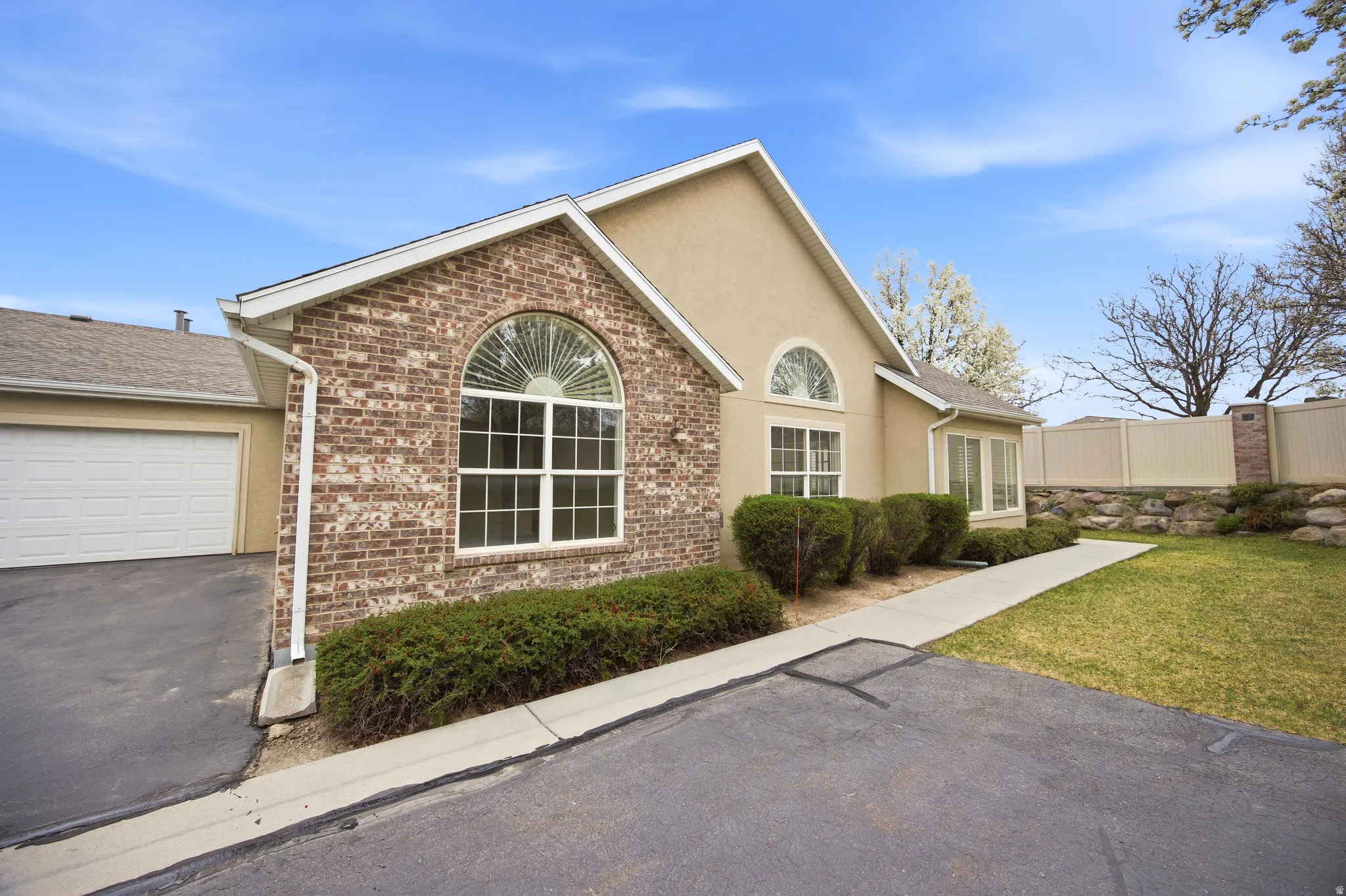 View of front facade featuring stucco siding, brick siding, an attached garage, and driveway