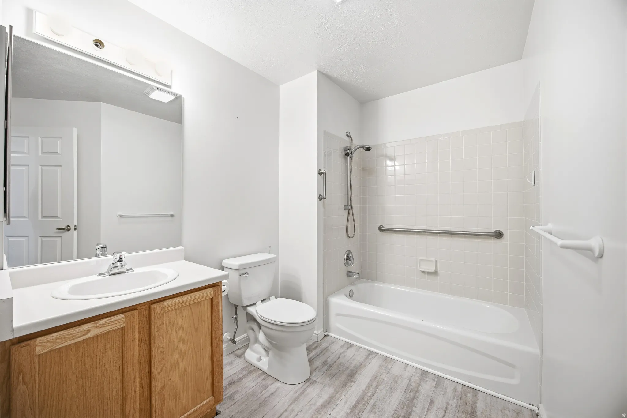 Bathroom featuring vanity, shower / bath combination, and light wood-style flooring