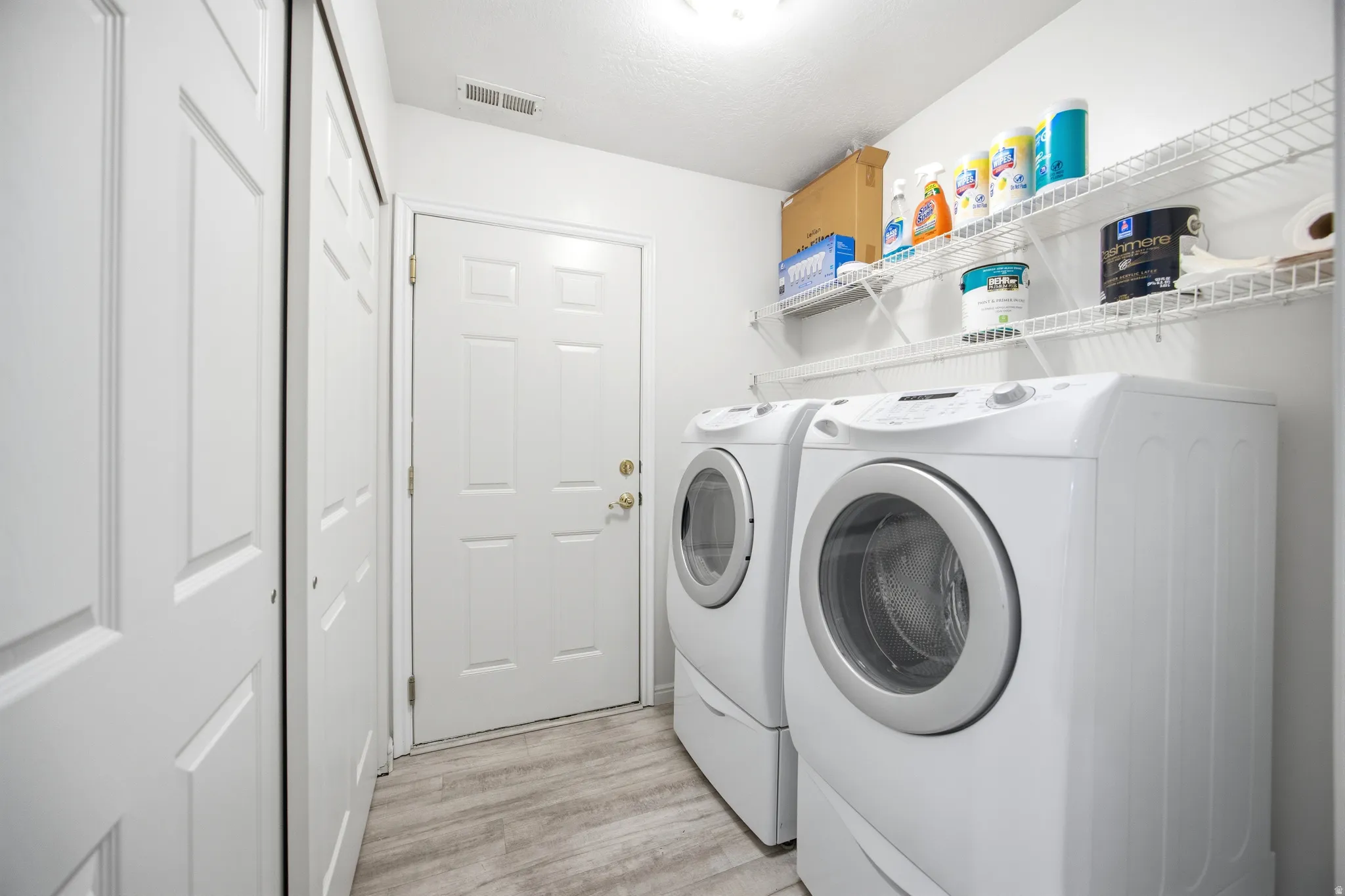 Laundry room featuring washing machine and clothes dryer and light wood finished floors