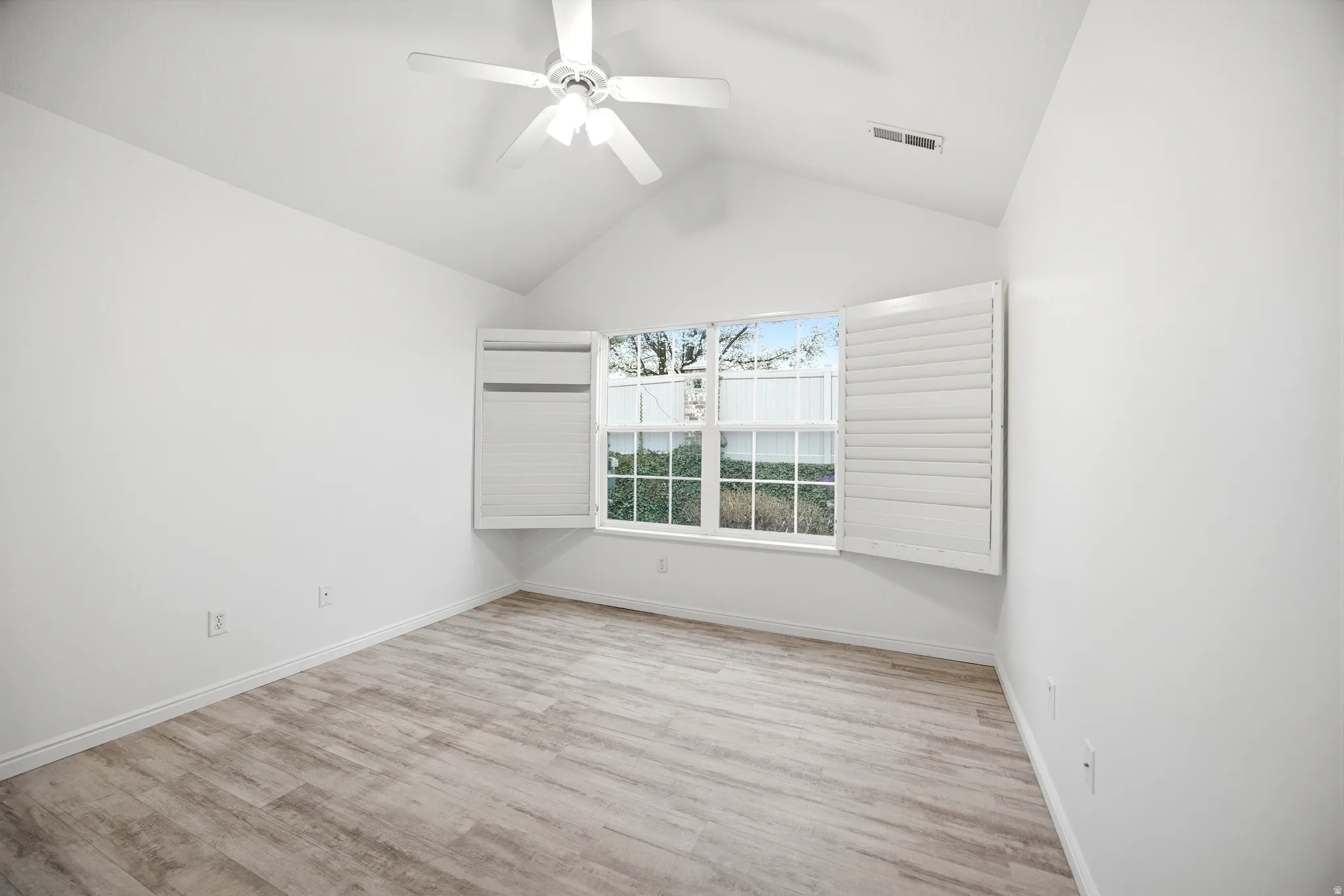 Empty room with ceiling fan and light wood-type flooring