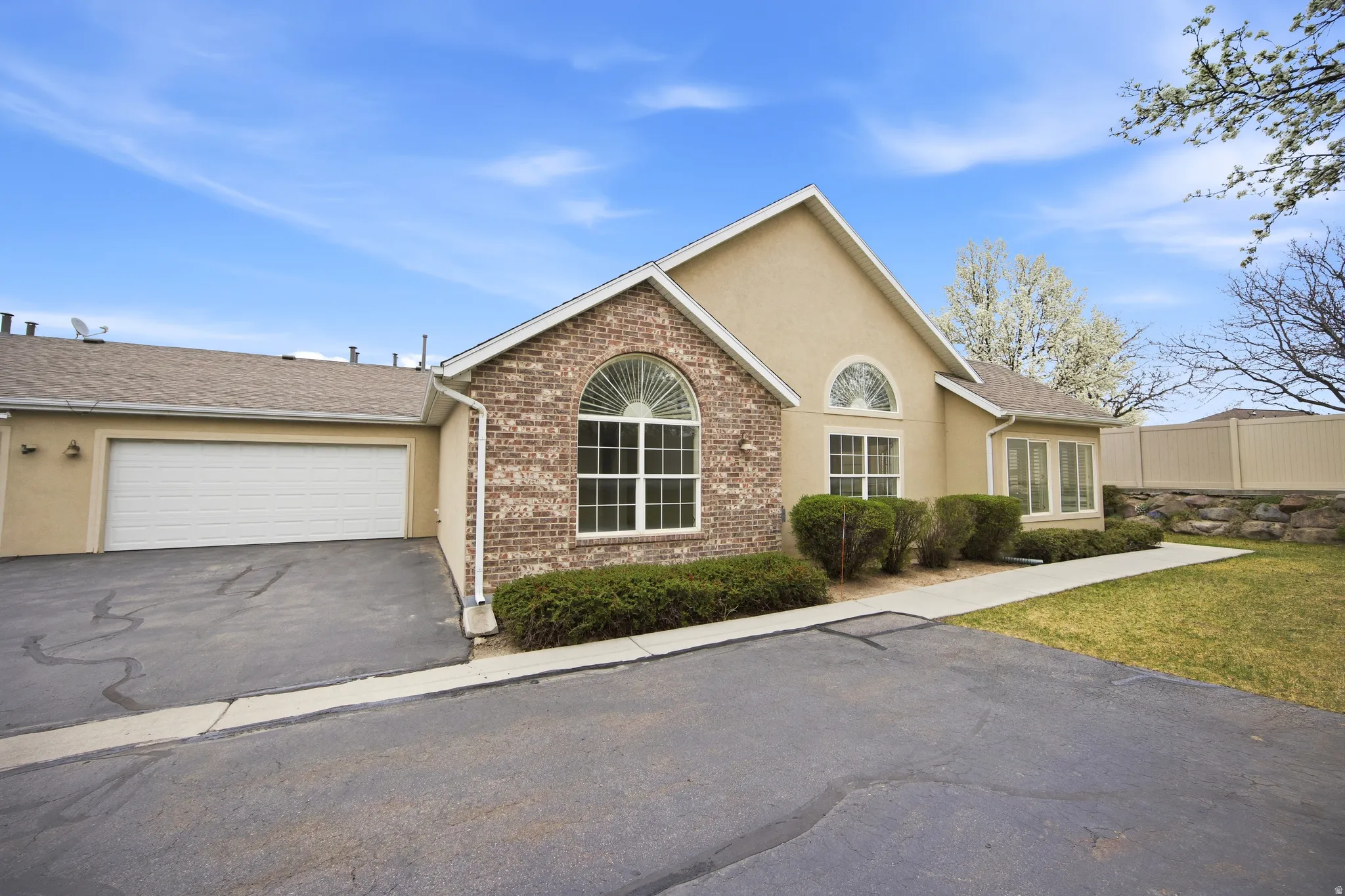 Ranch-style house featuring stucco siding, brick siding, an attached garage, asphalt driveway, and roof with shingles