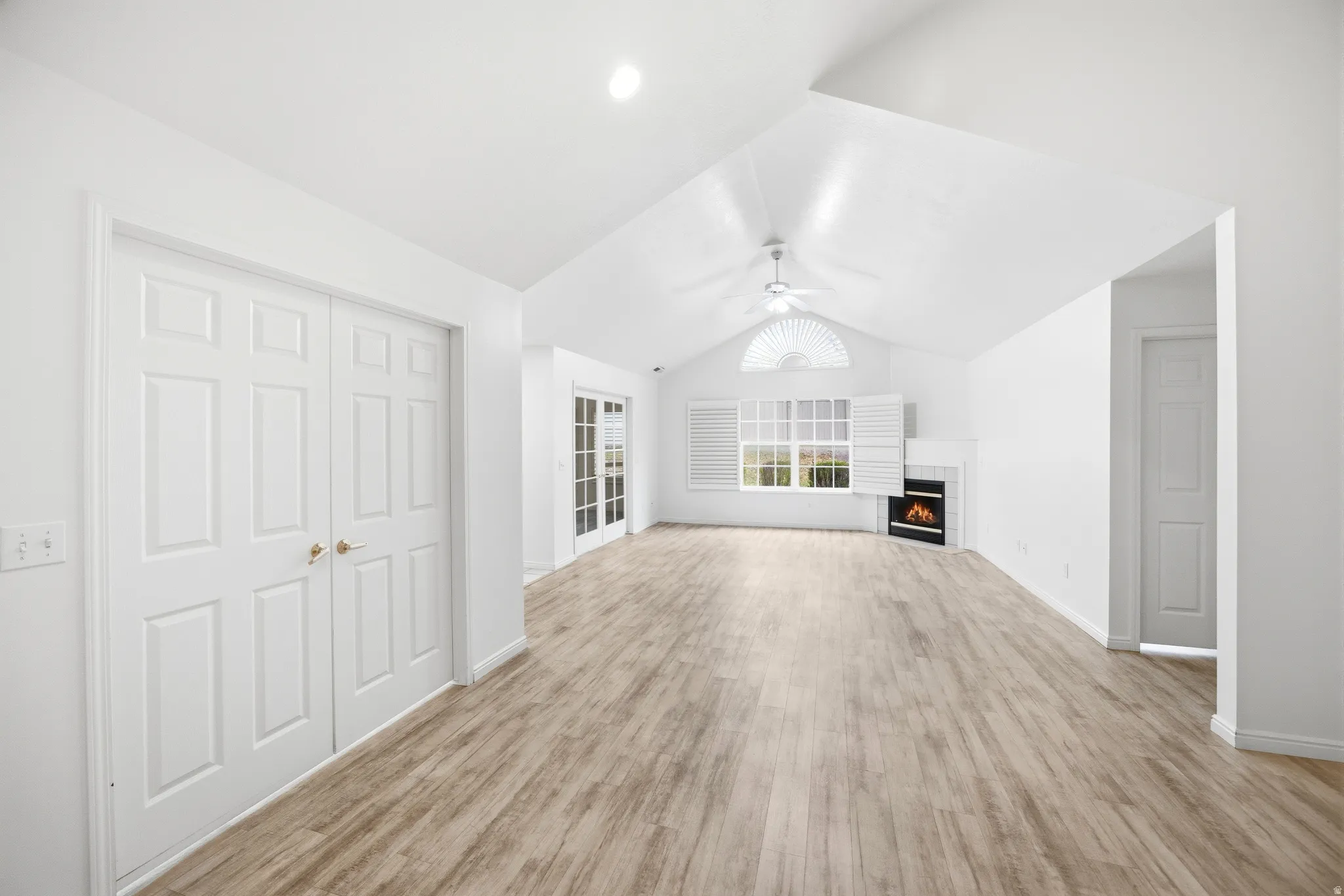 Unfurnished living room featuring a tiled fireplace, ceiling fan, and light wood-type flooring