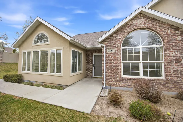 View of front of home featuring a shingled roof, brick siding, and stucco siding