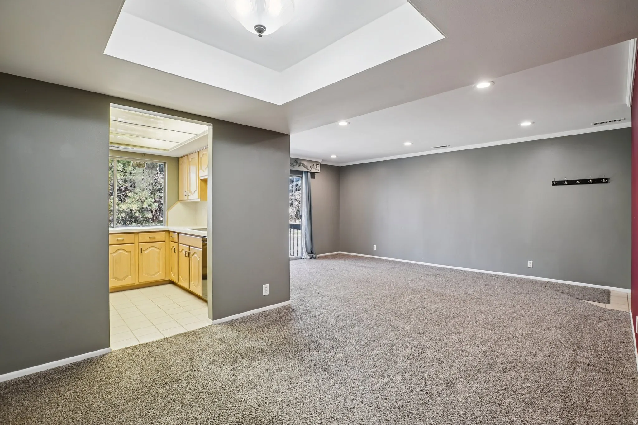 Bar featuring light colored carpet, light countertops, recessed lighting, light wood finish cabinetry, and a raised ceiling