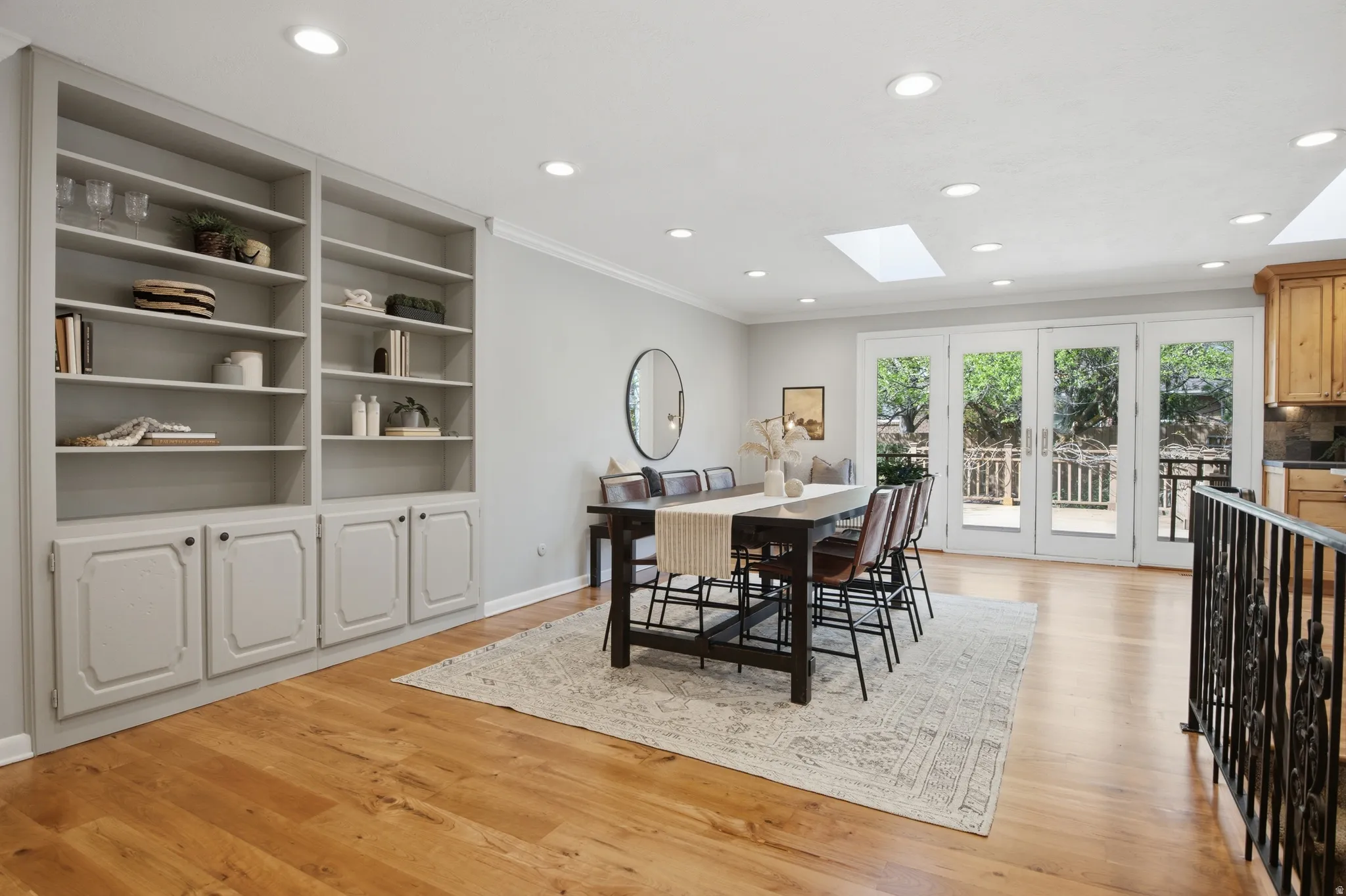 Dining space featuring a skylight, crown molding, light wood-type flooring, recessed lighting, and built in shelves