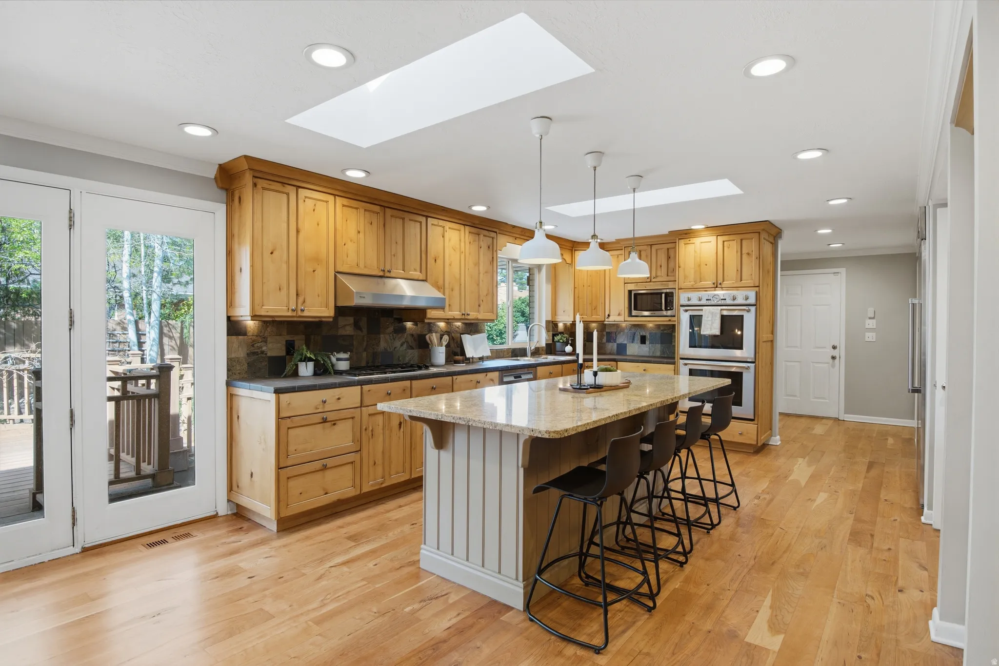Kitchen featuring a kitchen bar, decorative backsplash, stainless steel appliances, a kitchen island, and light wo flooring