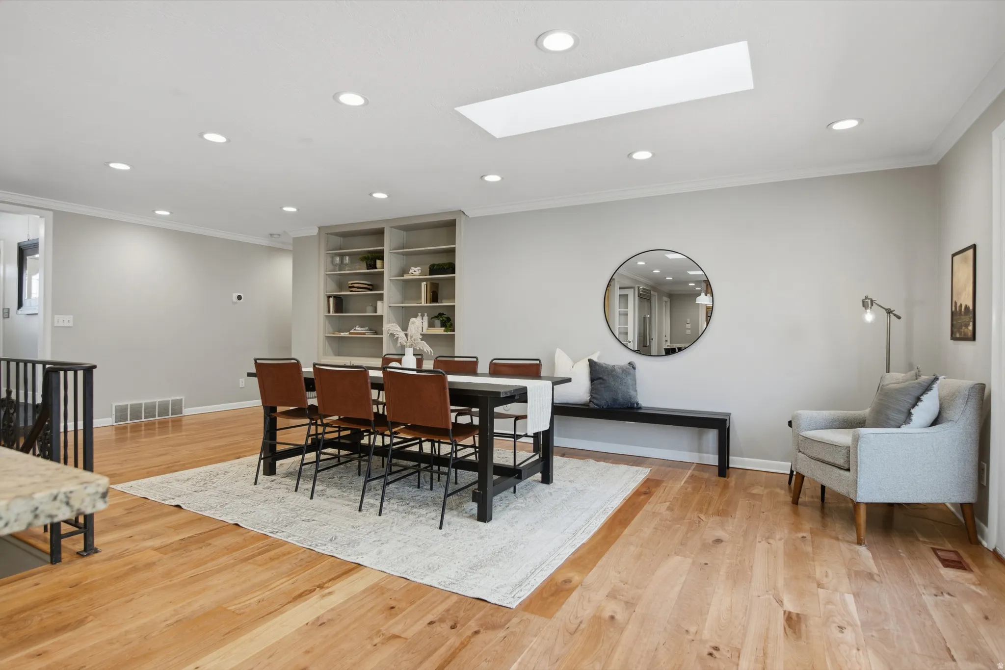 Dining room with a skylight, light wood-style flooring, ornamental molding, and recessed lighting