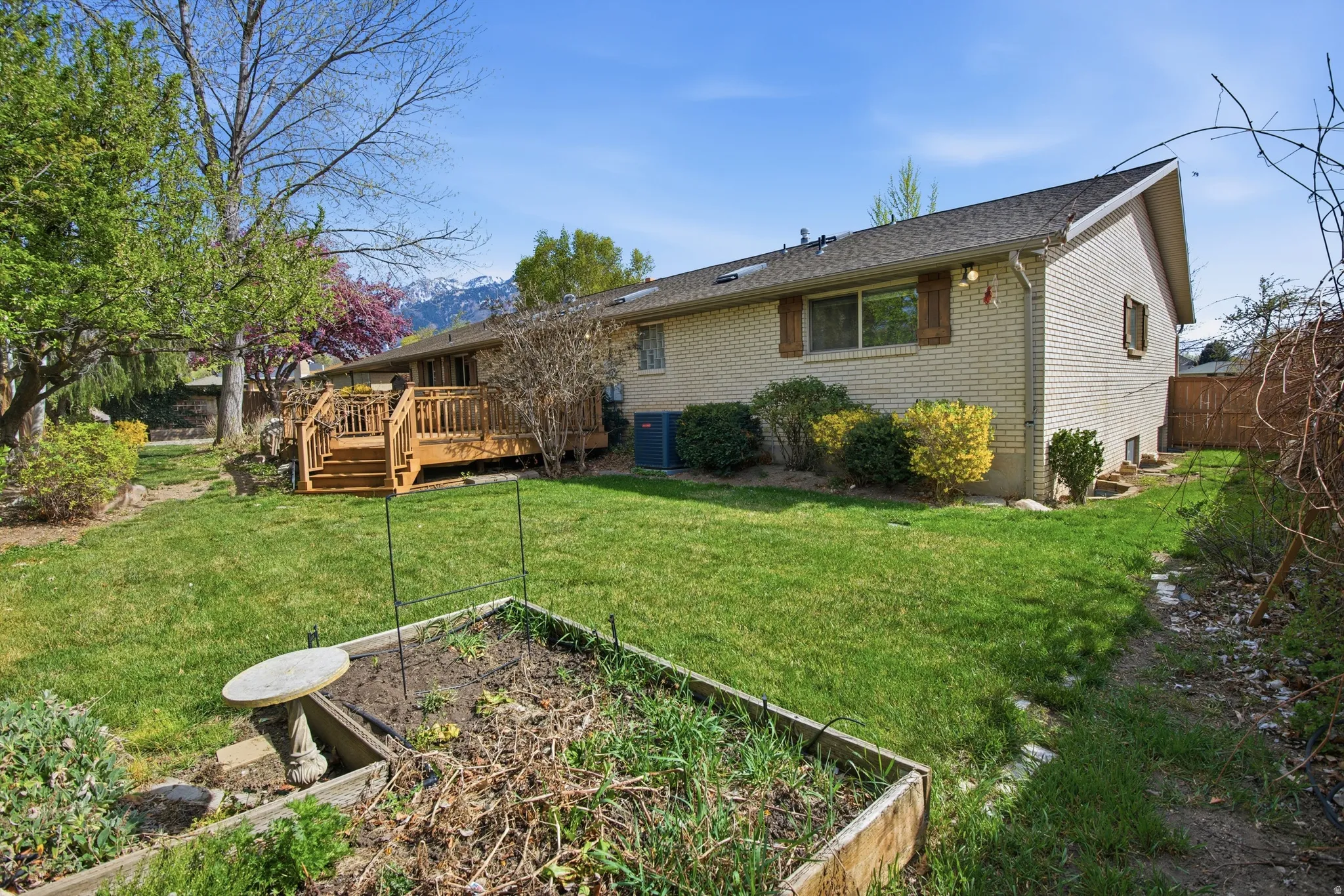 Back of house with a deck, brick siding, and a vegetable garden