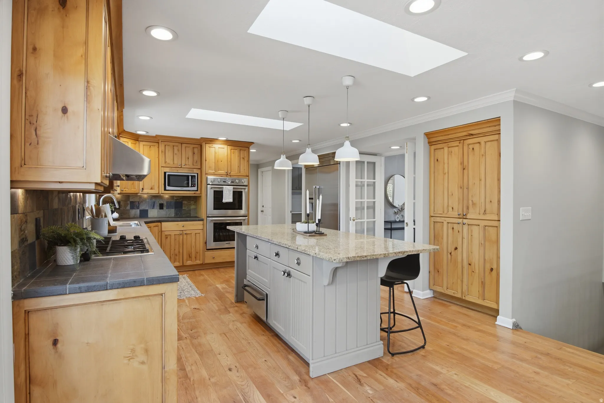 Kitchen featuring tasteful backsplash, ornamental molding, a breakfast bar, a skylight, and a center island