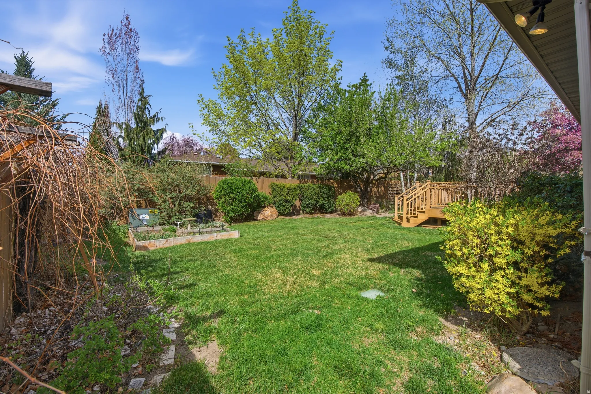 Fenced backyard featuring a wooden deck and a vegetable garden