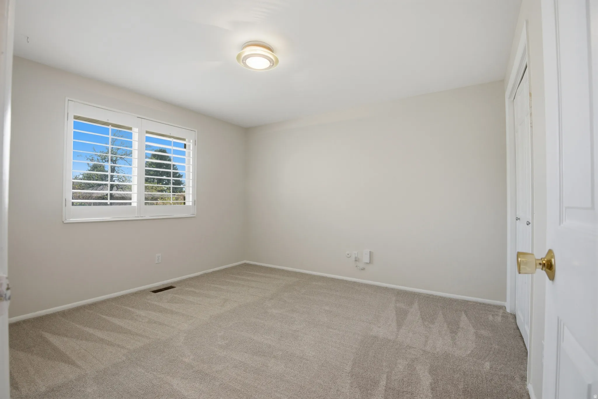 Spare room featuring light carpet and baseboards