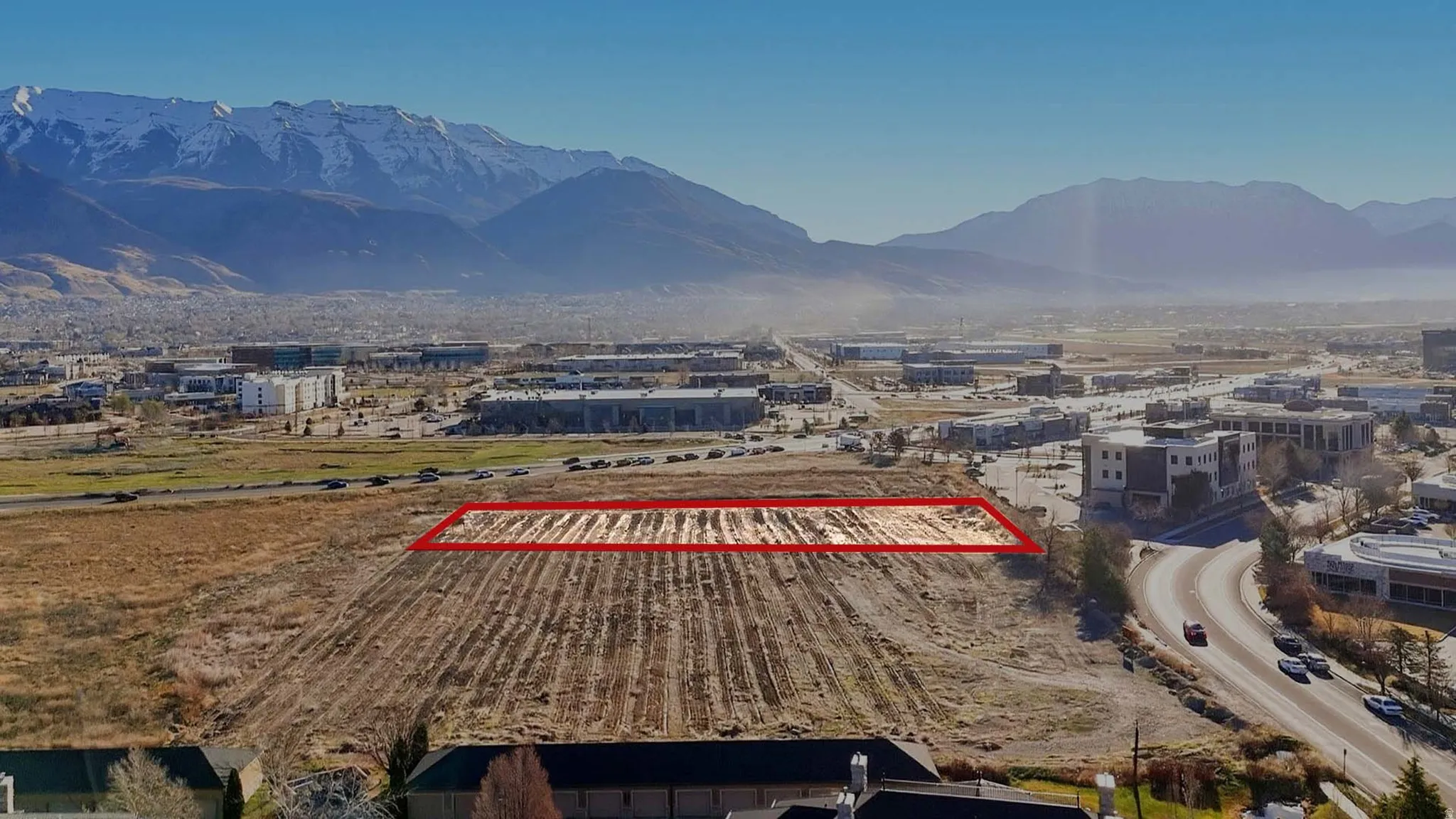 Aerial view of sparsely populated area featuring property parcel outlined and a mountain backdrop. Facing East