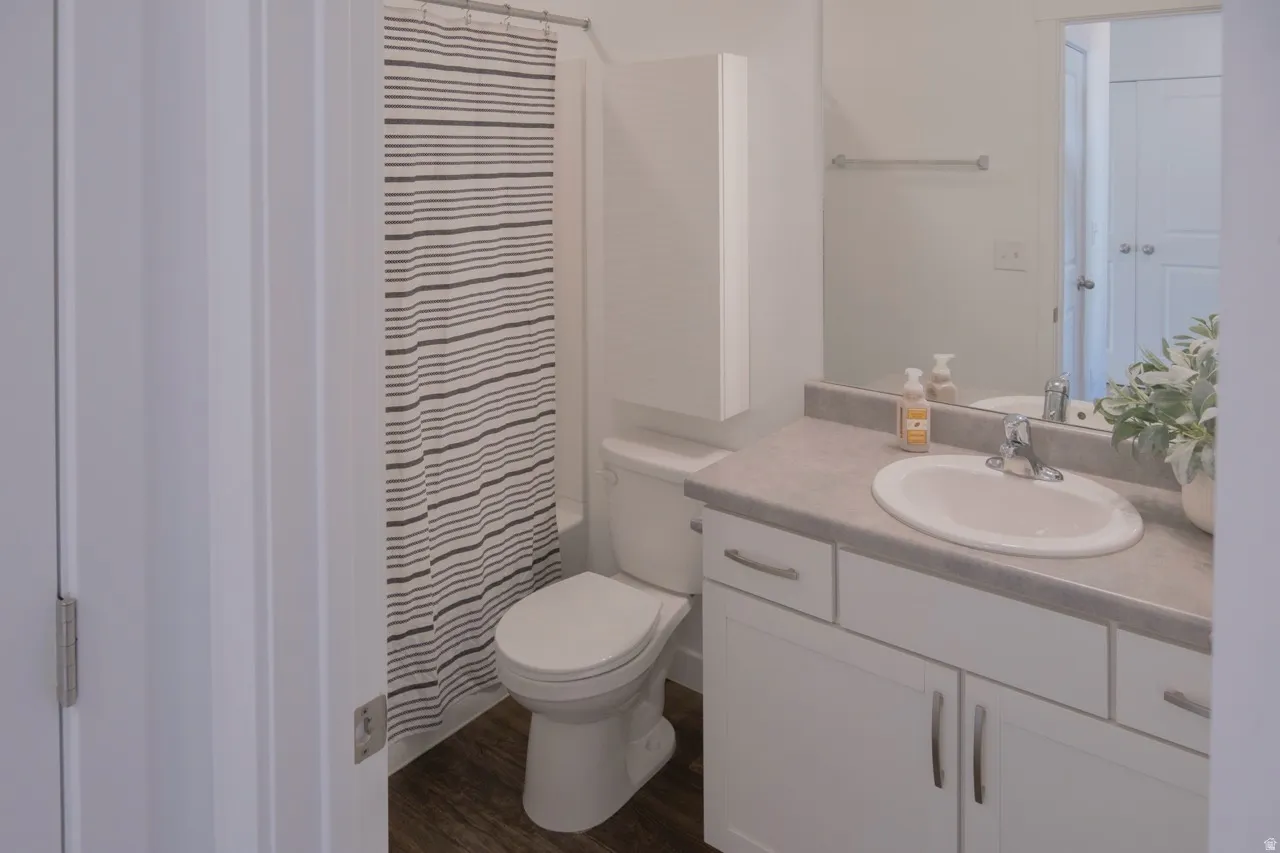 Bathroom featuring vanity, dark wood finished floors, and shower / bath combo with shower curtain