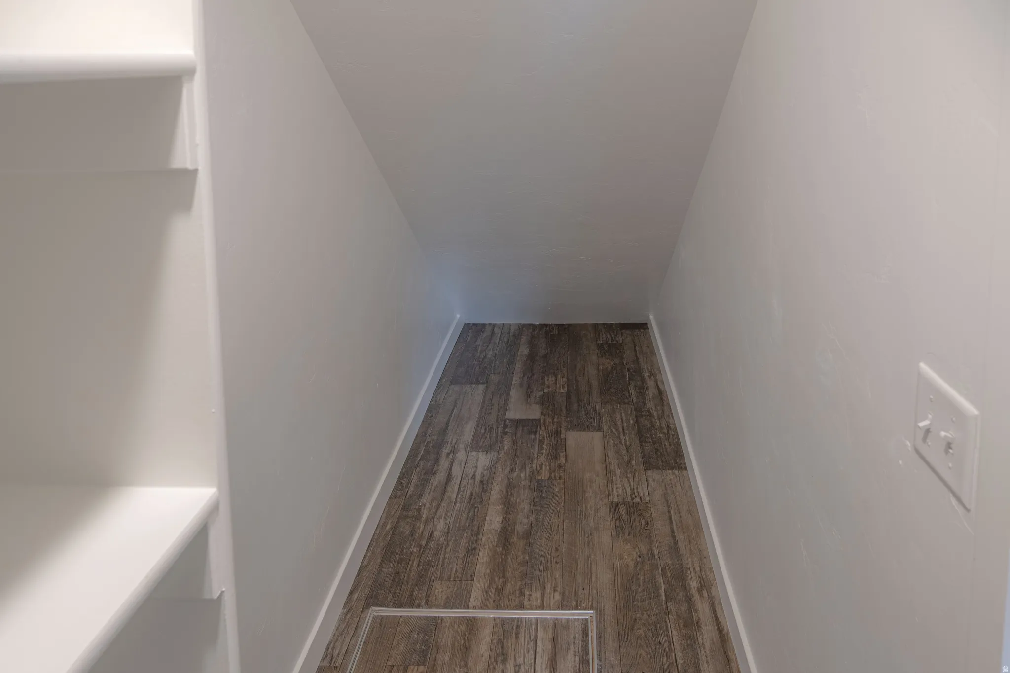 Corridor with dark wood-style floors and baseboards