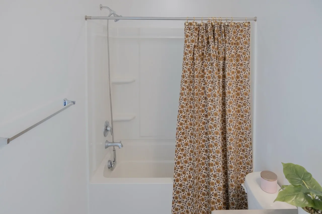 Bathroom featuring toilet and shower / bath combo with shower curtain