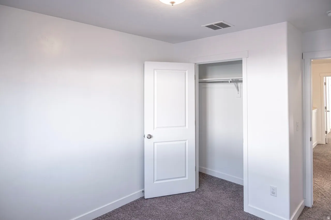 Unfurnished bedroom with dark carpet and a closet