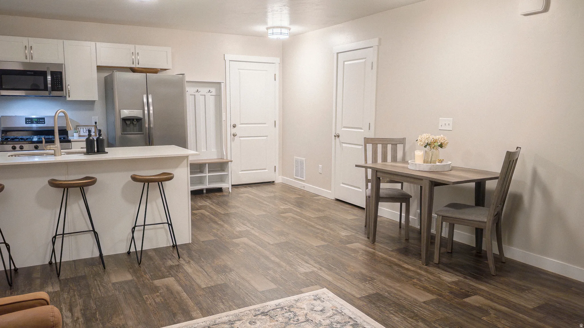 Kitchen with stainless steel appliances, white cabinetry, dark wood finished floors, and a kitchen breakfast bar