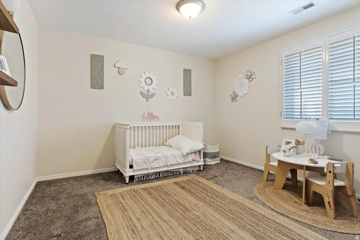 Bedroom featuring a nursery area and dark colored carpet