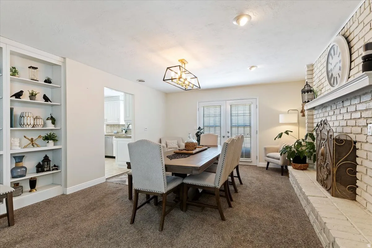 Dining space featuring a brick fireplace, dark carpet, french doors, and built in features