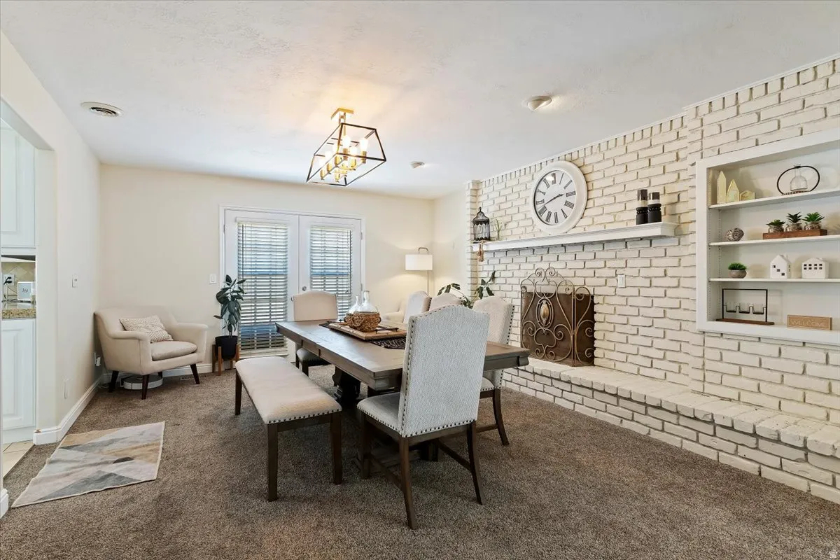 Dining space with a fireplace, dark colored carpet, built in shelves, and hanging lights