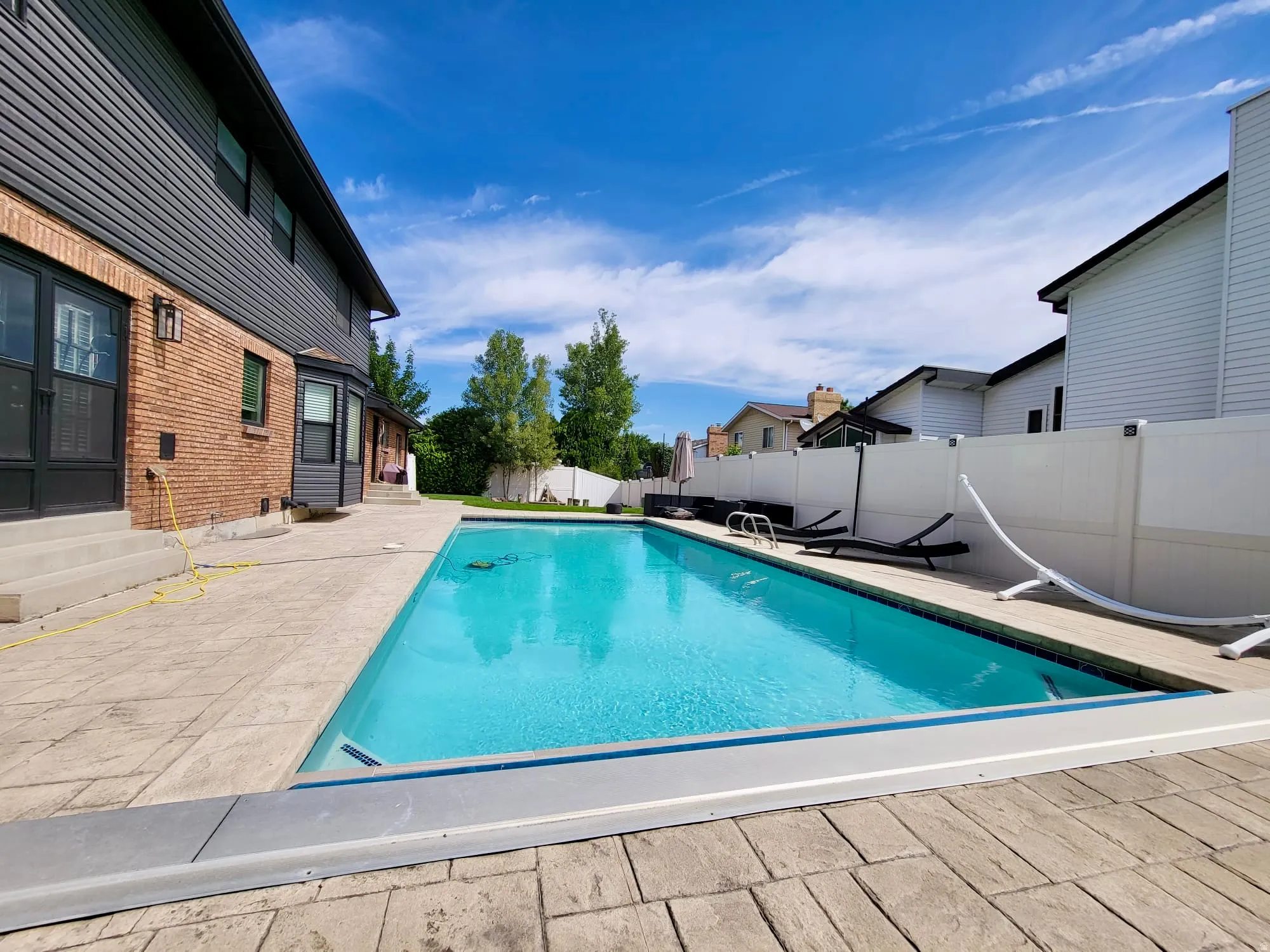 View of swimming pool with entry steps, patio surround, and a fenced backyard
