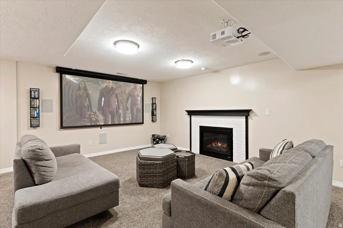 Carpeted home theater room featuring a textured ceiling and a glass covered fireplace