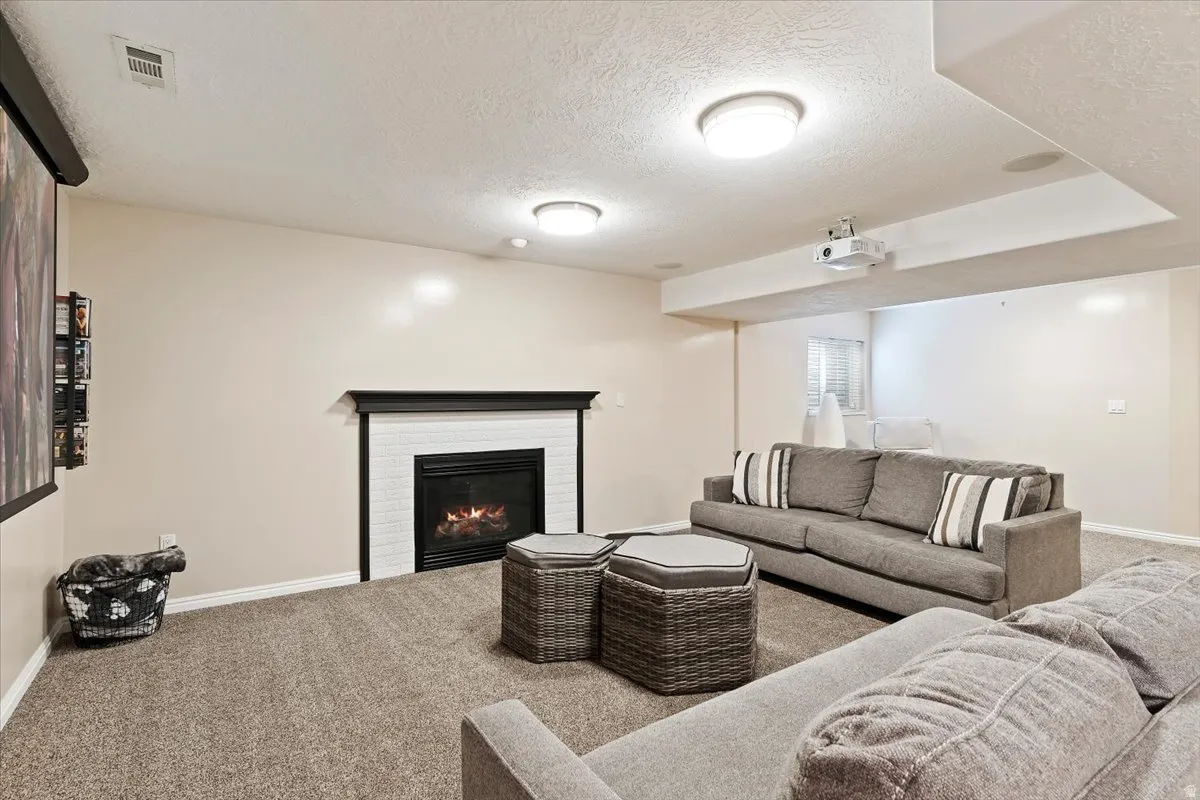 Carpeted living area featuring a textured ceiling and a glass covered fireplace