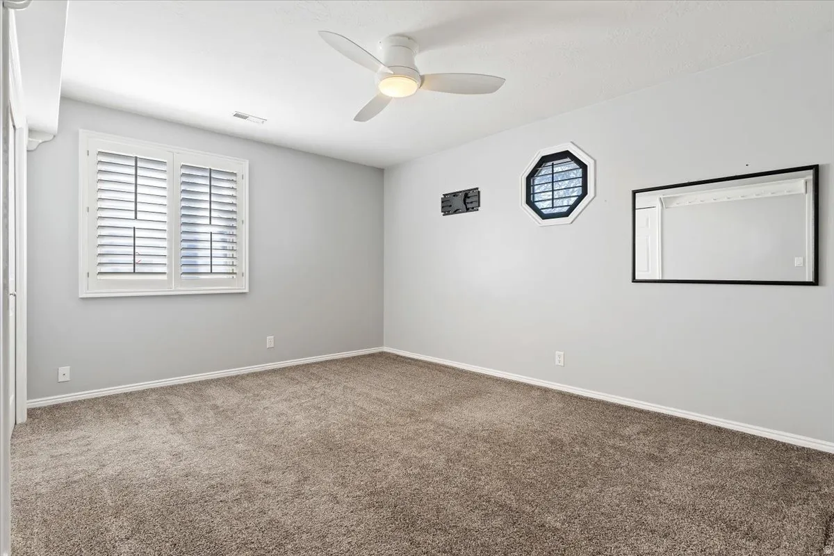 Carpeted empty room featuring a ceiling fan and baseboards