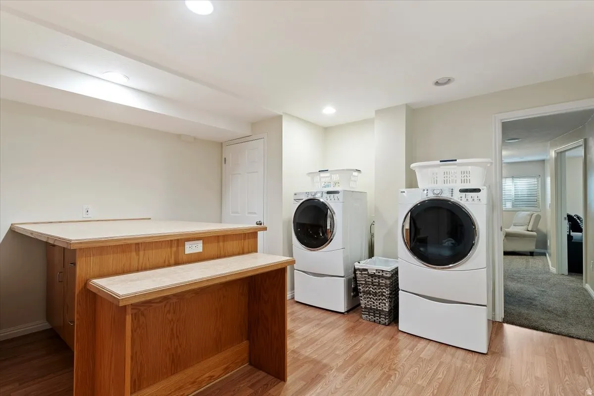 Laundry area featuring light wood-type flooring, washing machine and dryer, and recessed lighting