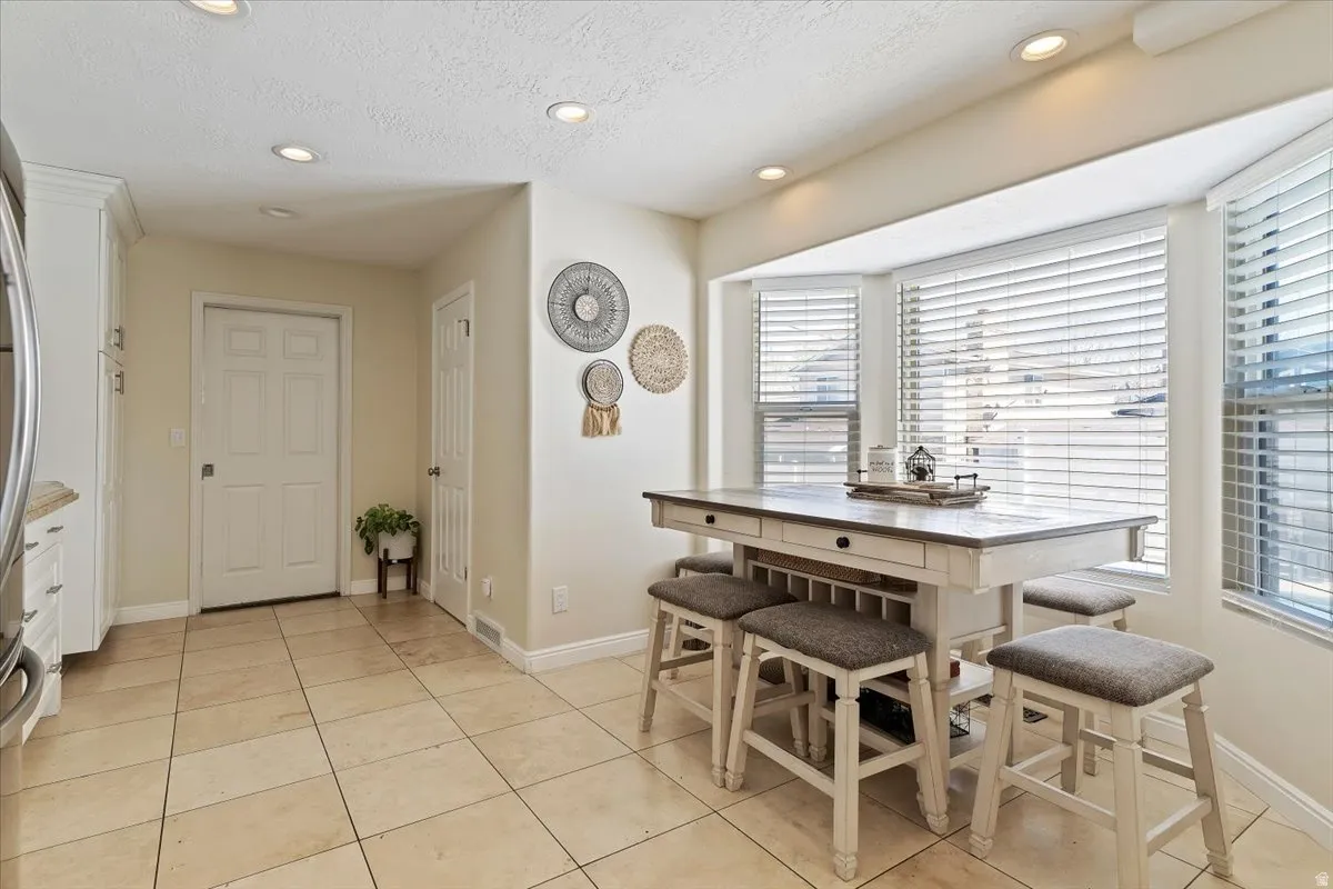 Dining area with recessed lighting, light tile patterned floors, and a textured ceiling