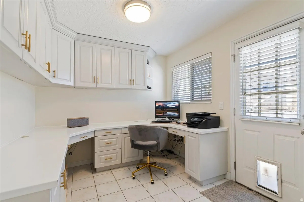 Home office with built in desk, light tile patterned floors, and a textured ceiling