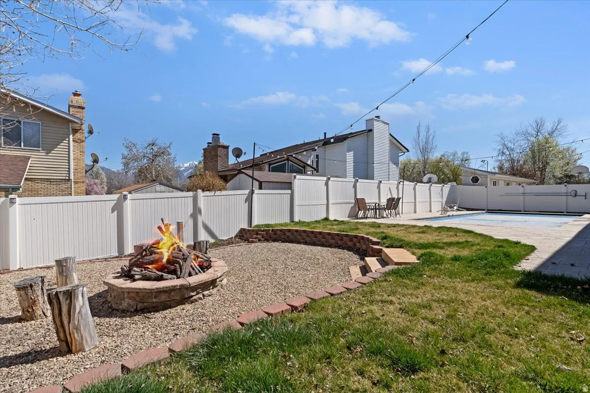Fenced backyard featuring a swimming pool, a fire pit, and a patio