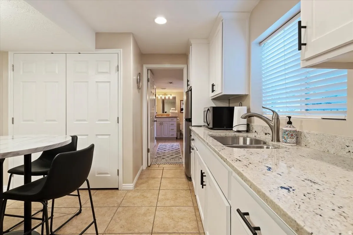 Kitchen featuring light stone counters, white cabinets, light tile patterned floors, stainless steel appliances, and recessed lighting