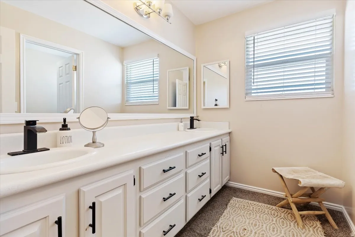 Full bathroom with double vanity and dark colored carpet