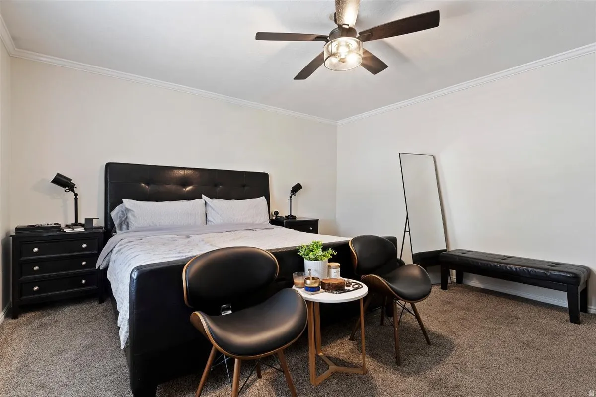 Carpeted bedroom featuring ornamental molding and a ceiling fan