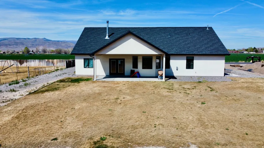 Rear view of house with stucco siding, roof with shingles, a water and mountain view, and a patio area