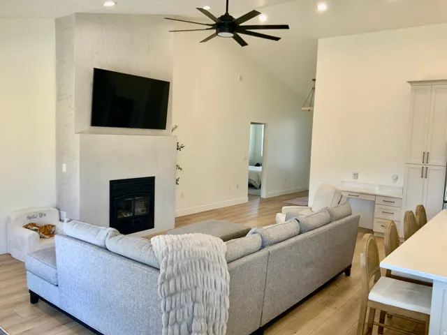 Living room featuring a ceiling fan, light wood-style flooring, a premium fireplace, vaulted ceiling, and recessed lighting
