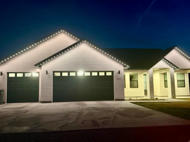 View of front facade with a garage, driveway, and brick siding