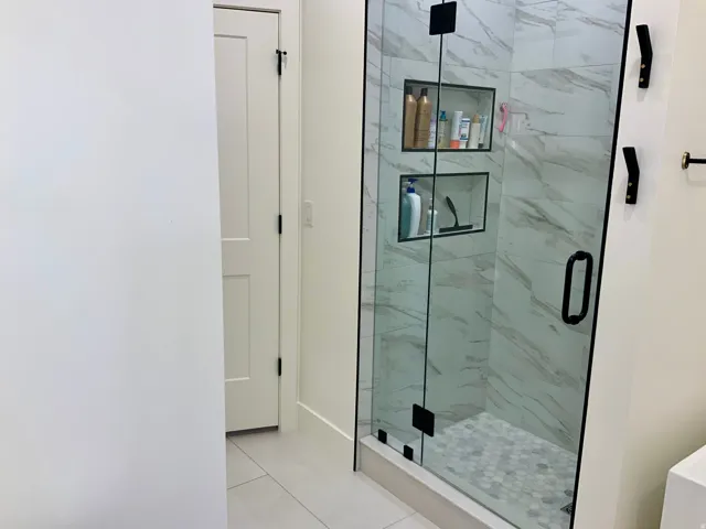 Full bathroom with a marble finish shower and light tile patterned floors