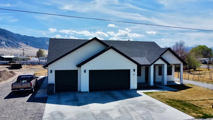 Modern farmhouse with a garage, a shingled roof, concrete driveway, and a mountain view