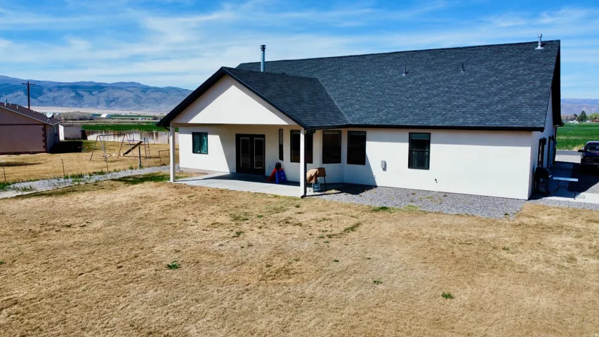 Back of property with a mountain view, roof with shingles, and stucco siding