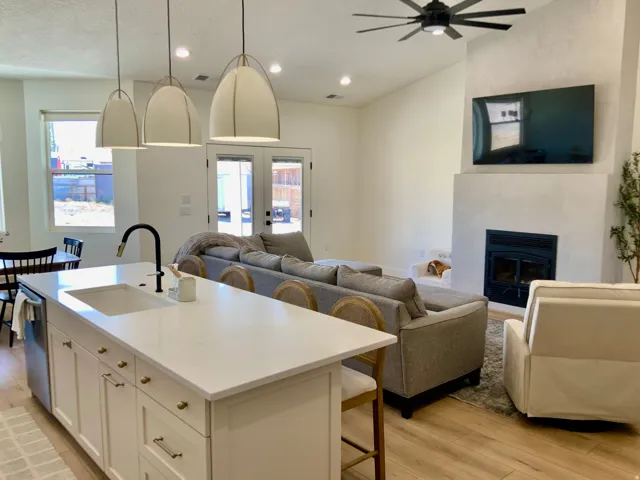 Kitchen with open floor plan, a kitchen bar, a kitchen island with sink, light wood-style floors, and white cabinets