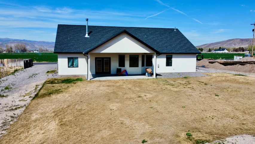 Back of property featuring a mountain view, a shingled roof, stucco siding, and a patio