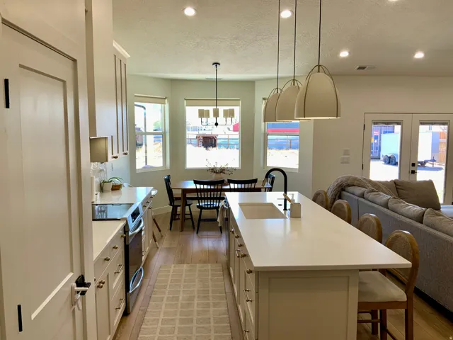 Kitchen featuring a kitchen bar, stainless steel electric range, light wood-style floors, a kitchen island with sink, and white cabinetry