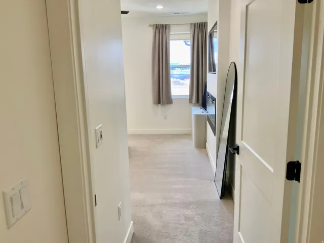 Hall featuring baseboards and light carpet